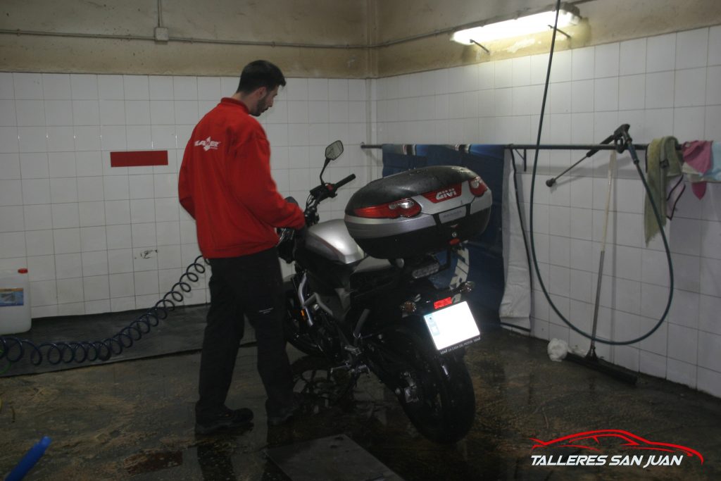 Imagen del encargado del lavadero lavando a mano la moto de uno de nuestros clientes